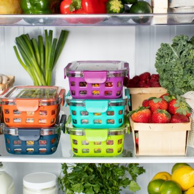 A stack of containers and produce in a refrigerator 