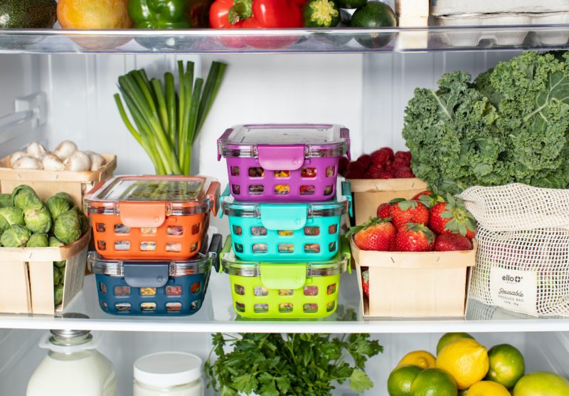 A stack of containers and produce in a refrigerator