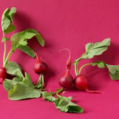 Four radishes sitting on a red background