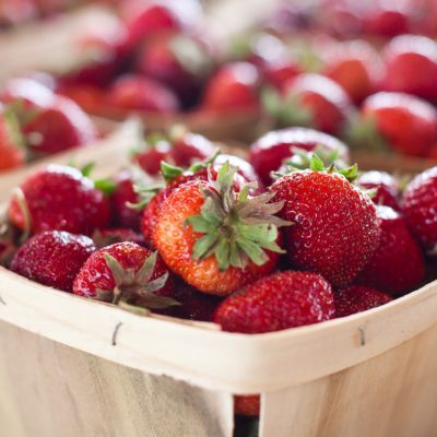 A farmers market table with baskets of red strawberries