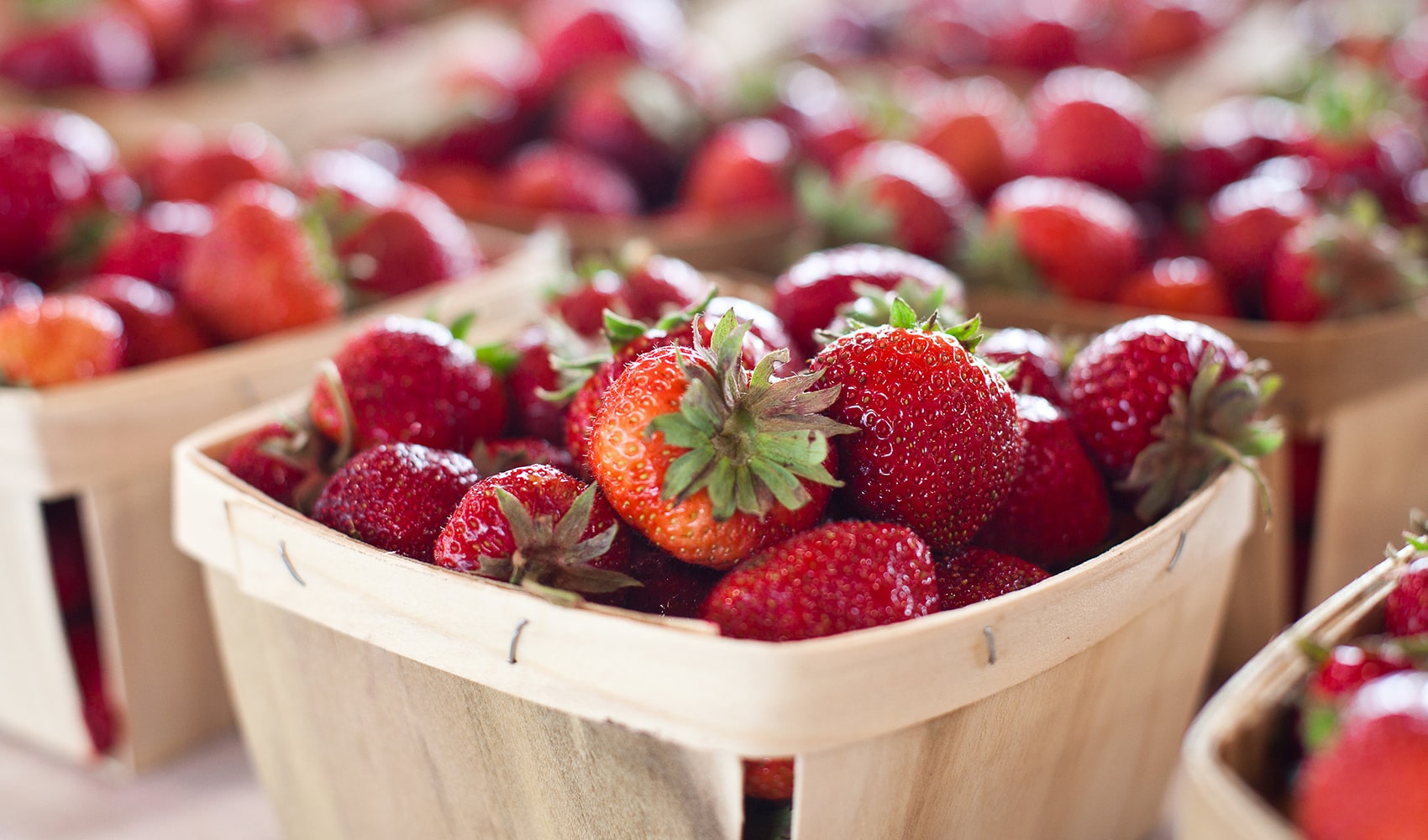 A farmers market table with baskets of red strawberries