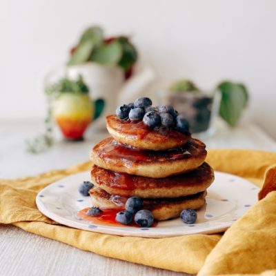 Photo of a stack of pancakes with blueberries on top.