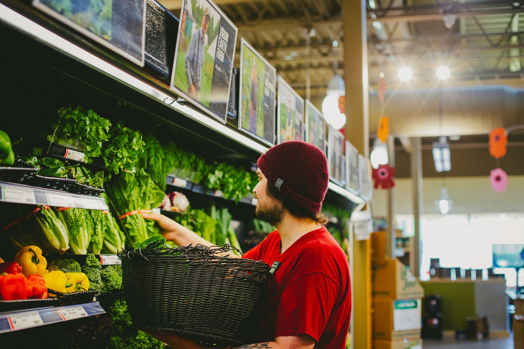 Grocery store employee stocks fresh lettuce on the shelf at the Marquette Food Co-op located in Marquette, Michigan.